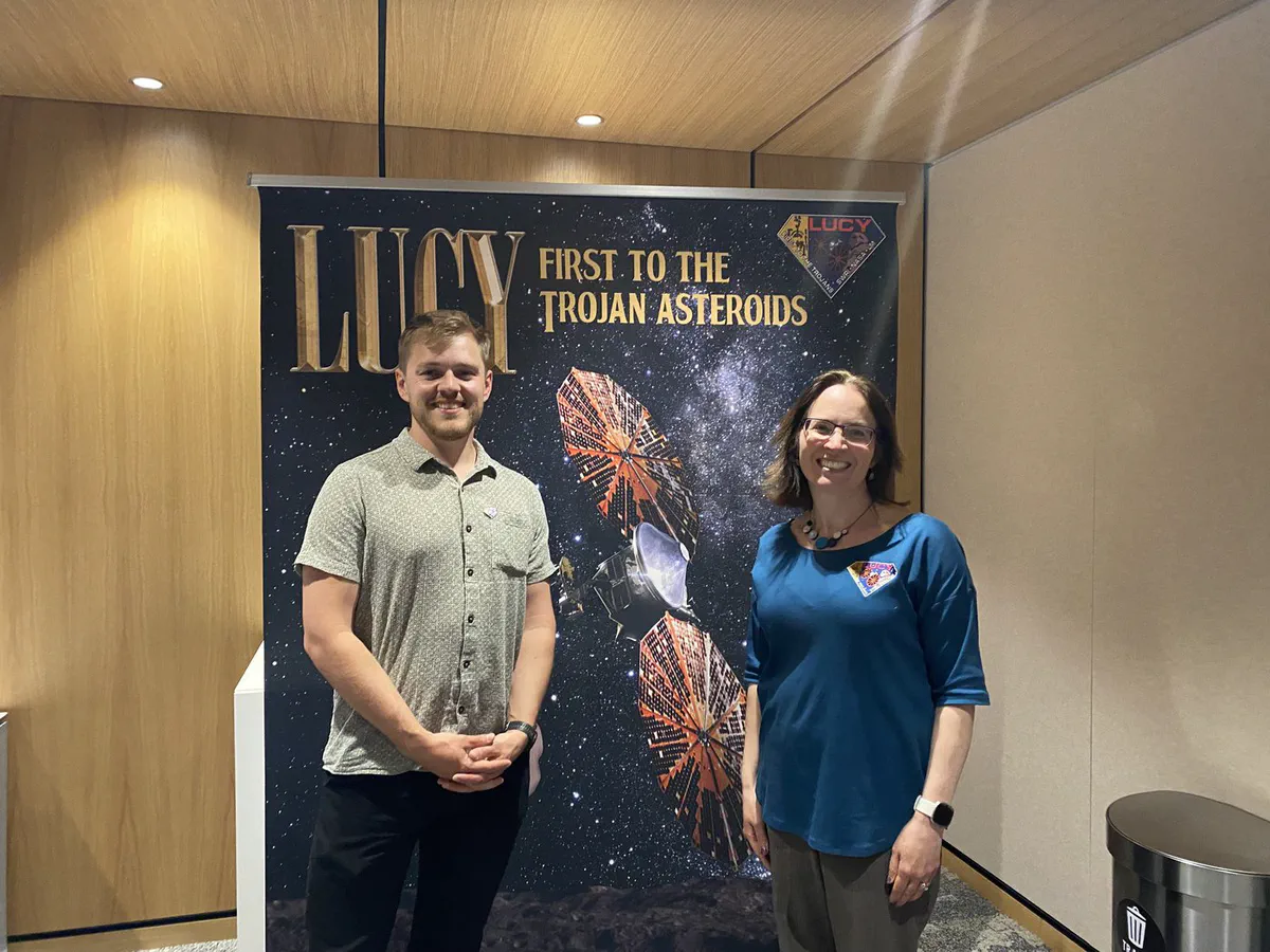 Duncan Lyster and Carly Howett in front of a Lucy mission banner in Boulder, Colorado